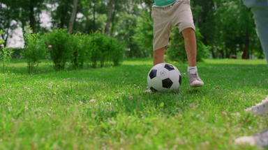 <strong>未知</strong>的男孩腿使足球锻炼特写镜头儿子培训足球爸爸